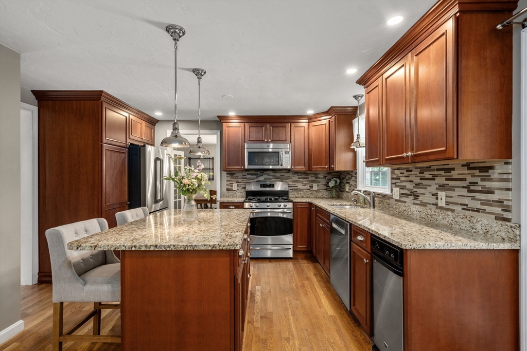 16 Jasmine Road Medway, MA 02053 - Photo 3 of 41 a kitchen with stainless steel appliances granite countertop a stove top oven a sink dishwasher a dining table and chairs with wooden floor