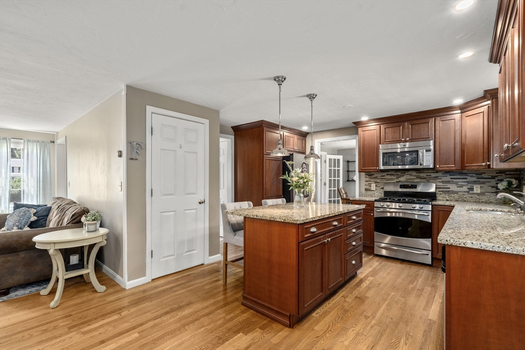 16 Jasmine Road Medway, MA 02053 - Photo 4 of 41 a kitchen with stainless steel appliances granite countertop a stove top oven a refrigerator a sink dishwasher and a dining table with wooden floor