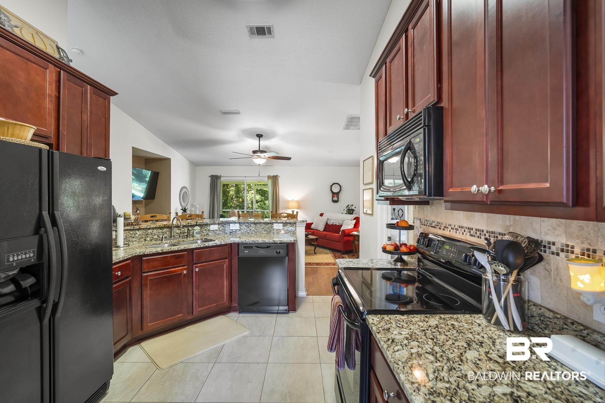 1802 South Bay Street Foley, AL 36535 - Photo 13 of 30 Kitchen featuring black appliances, reddish brown cabinets, a sink, backsplash, and lofted ceiling