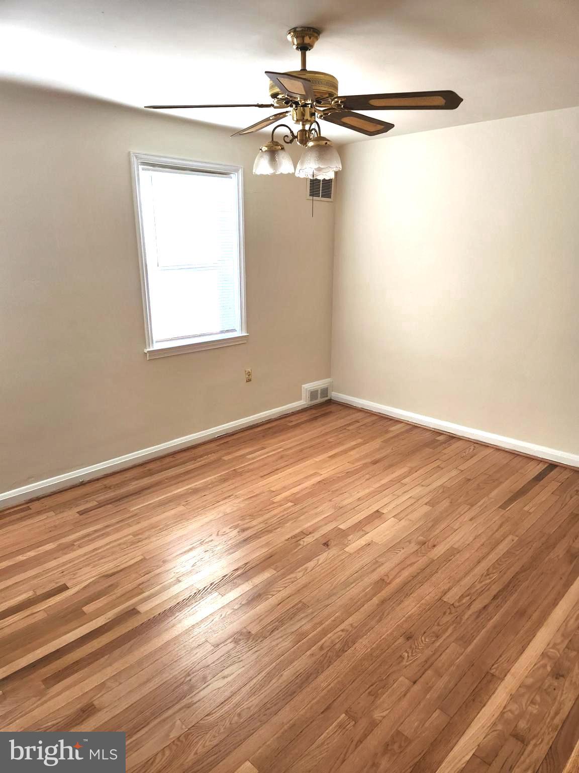 1330 Meridene Drive Baltimore, MD 21239 - Photo 11 of 15 an empty room with wooden floor fan and windows