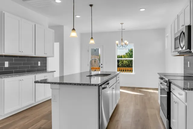 a kitchen with stainless steel appliances granite countertop a sink a stove and a wooden floors