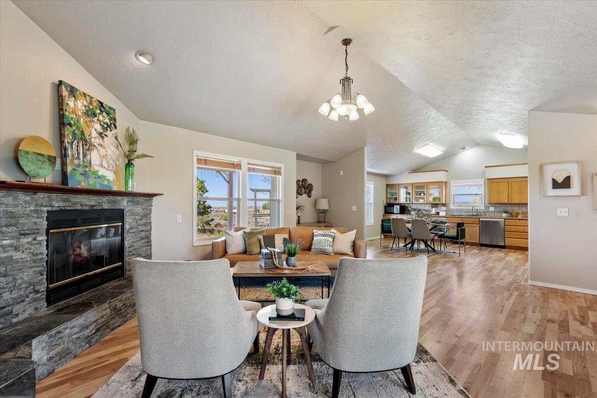 147 East Indian Crk Road Boise, ID 83716 - Photo 11 of 43 Spacious living area featuring a stone-clad fireplace with a wood mantel, vaulted ceilings, and large windows