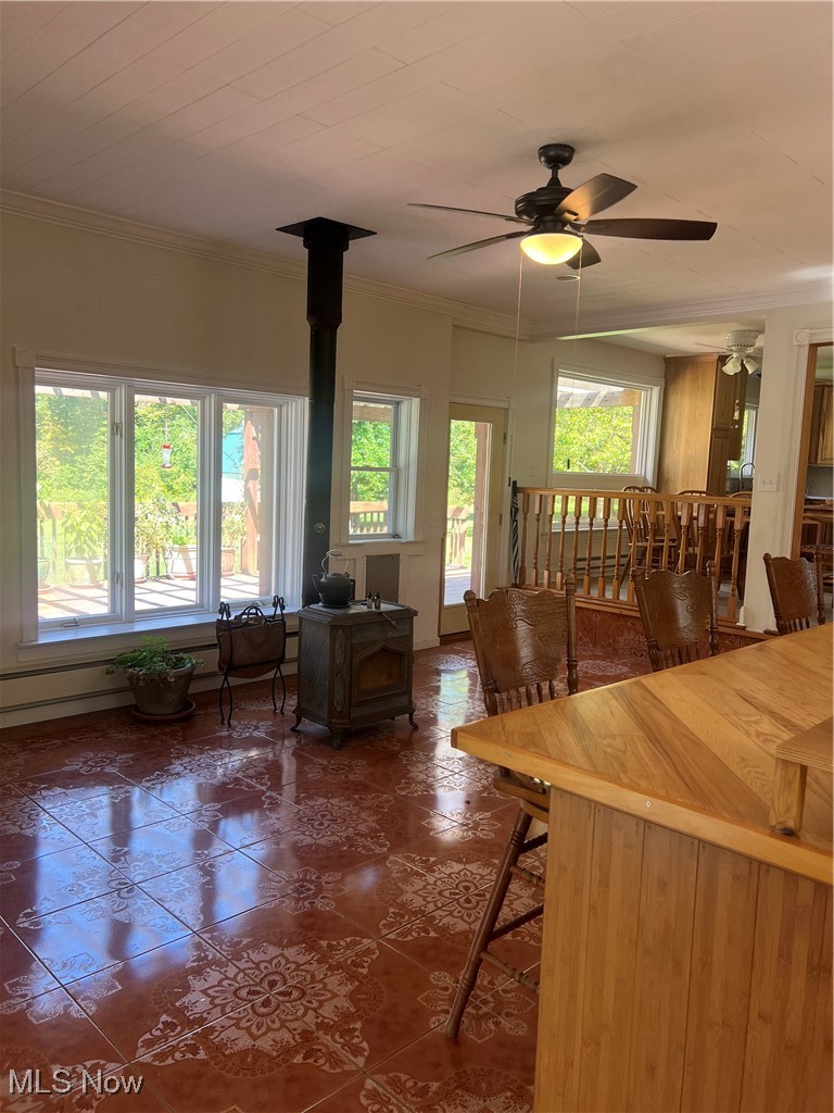 6171 Barrett Road Geneva, OH 44041 - Photo 15 of 38 Living area featuring a wood stove, ornamental molding, dark tile patterned flooring, and a ceiling fan