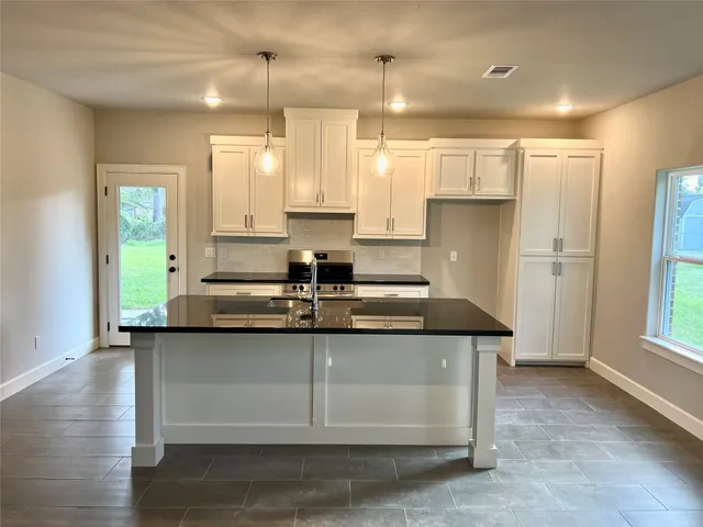a kitchen with kitchen island granite countertop a sink cabinets and wooden floor