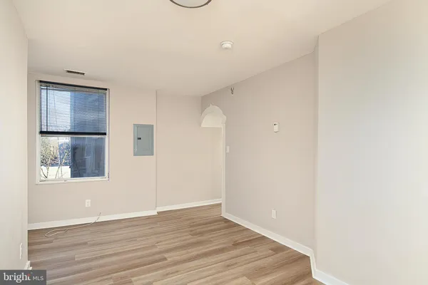 a view of an empty room with wooden floor and a window