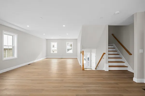 a view of an empty room with wooden floor and stairs