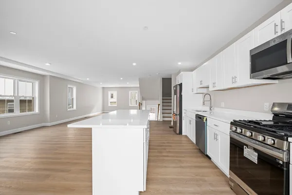 a kitchen with stainless steel appliances granite countertop a stove top oven a sink dishwasher and a refrigerator with wooden floor