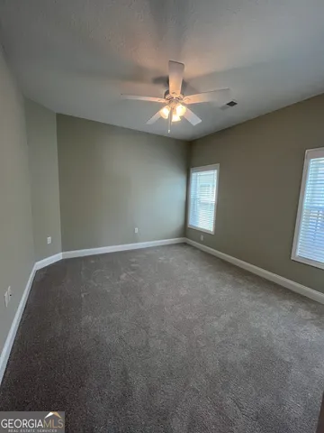 en empty room with windows and ceiling fan