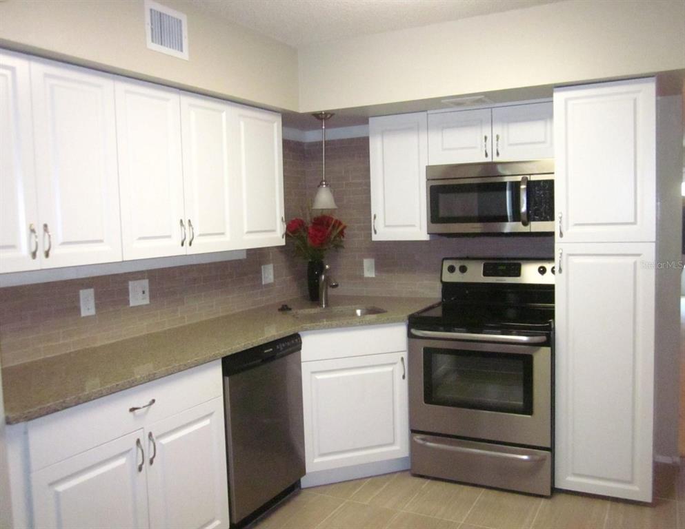 2456 Ecuadorian Way, Unit 46 Clearwater, FL 33763 - Photo 18 of 65 a kitchen with white cabinets and stainless steel appliances