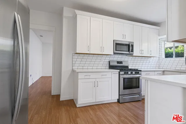 a kitchen with granite countertop white cabinets and stainless steel appliances