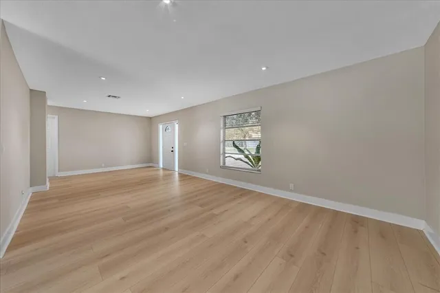 a view of an empty room with wooden floor and a window