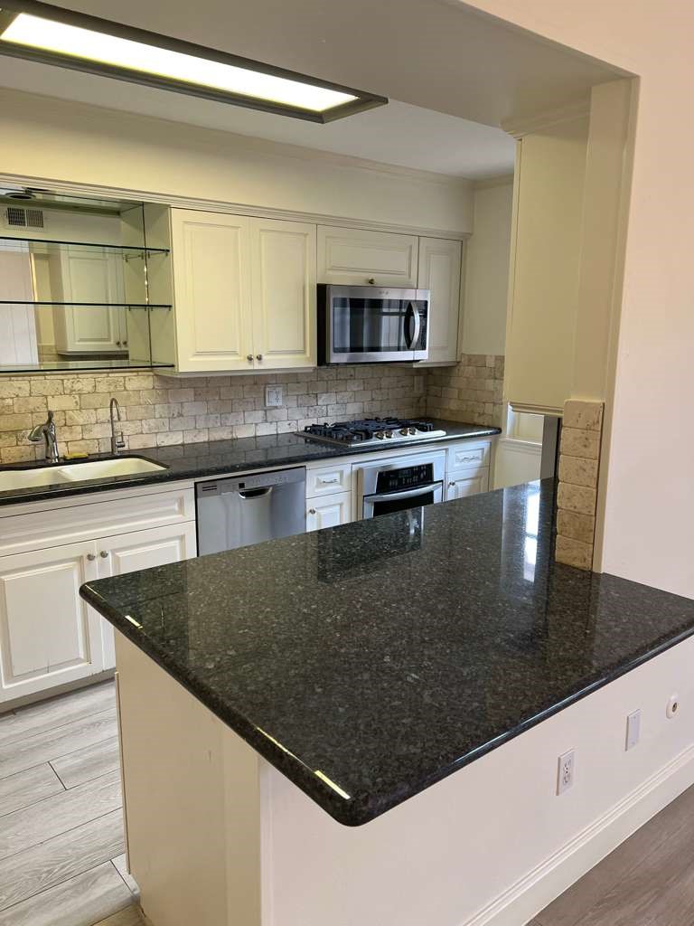 5817 Valley Forge Drive, Unit 90 Houston, TX 77057 - Photo 9 of 21 a kitchen with stainless steel appliances granite countertop a sink a stove counter space and wooden floor