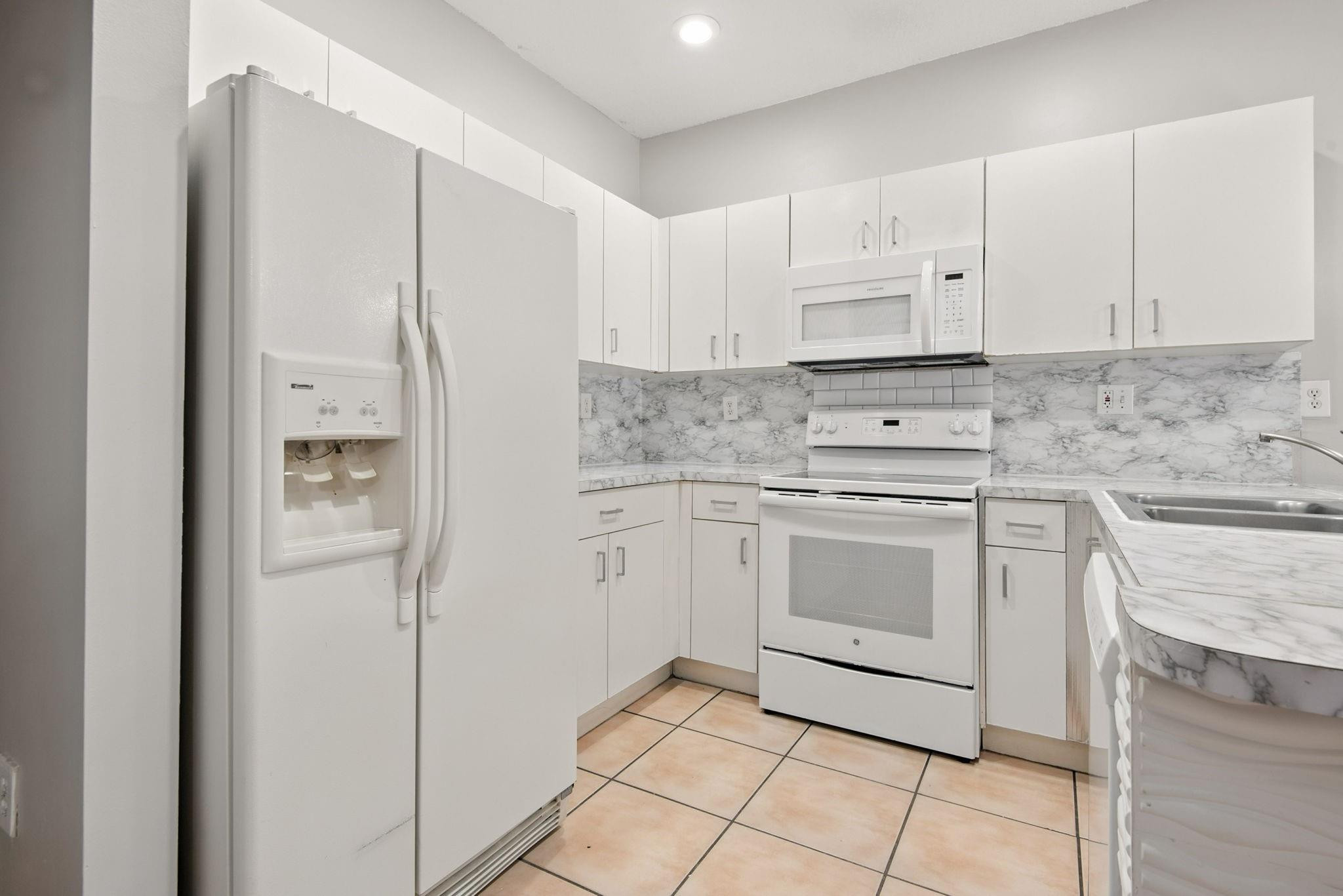 11368 Southwest 230th Terrace Miami, FL 33170 - Photo 7 of 37 a kitchen with white cabinets and white appliances