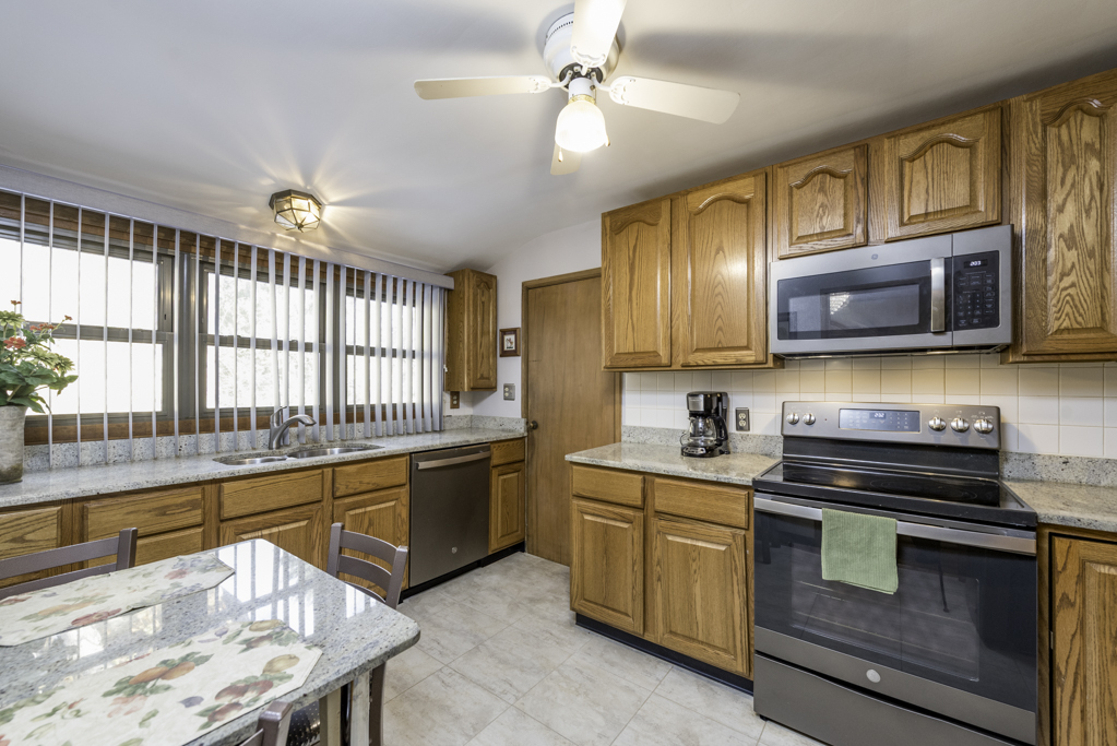 1118 Shiloh Boulevard Zion, IL 60099 - Photo 13 of 33 a kitchen with stainless steel appliances kitchen island granite countertop a stove sink and microwave
