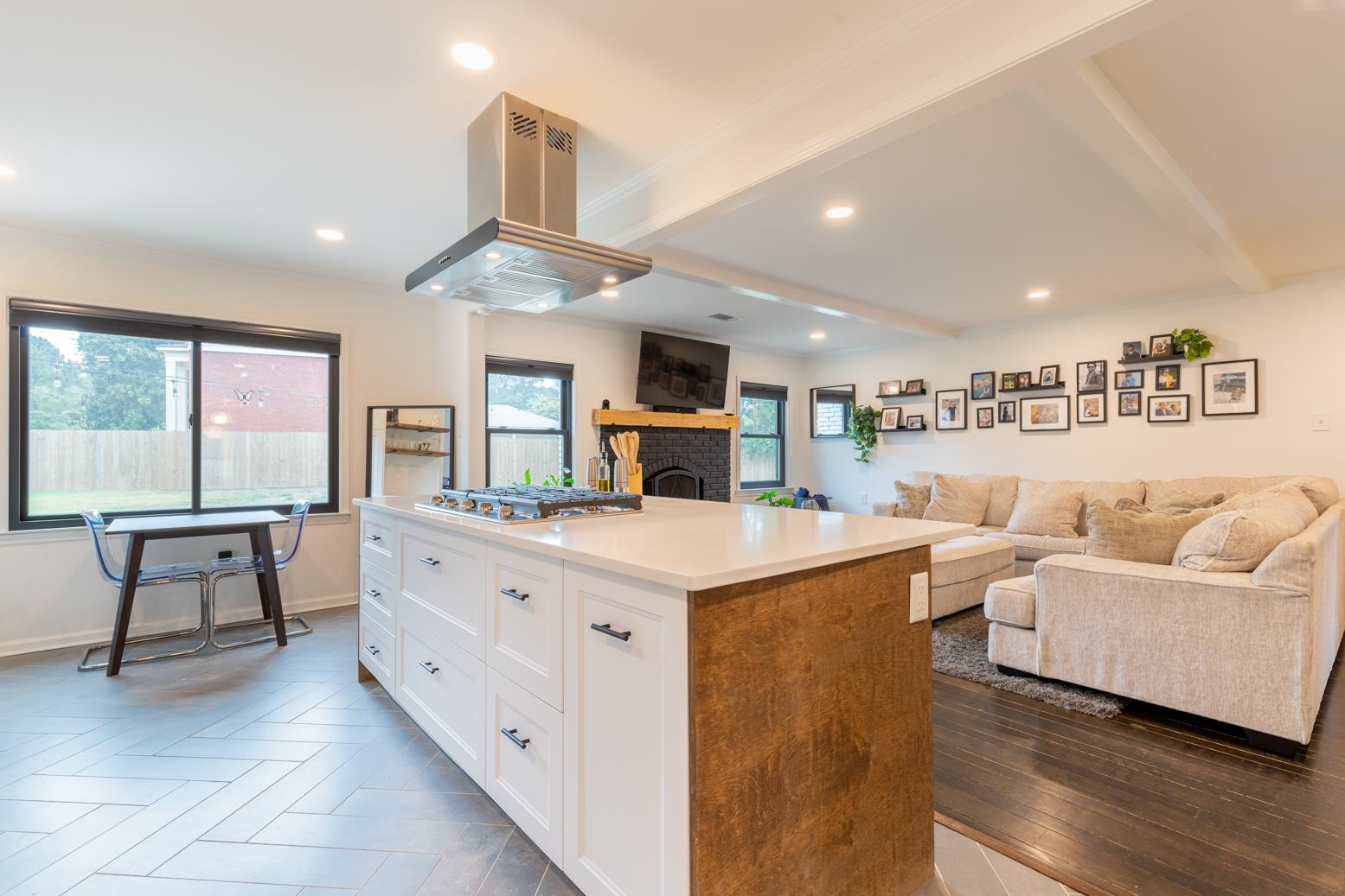6270 Quince Road Memphis, TN 38119 - Photo 8 of 28 Kitchen with stainless steel gas cooktop, white cabinetry, a brick fireplace, a center island, and island exhaust hood
