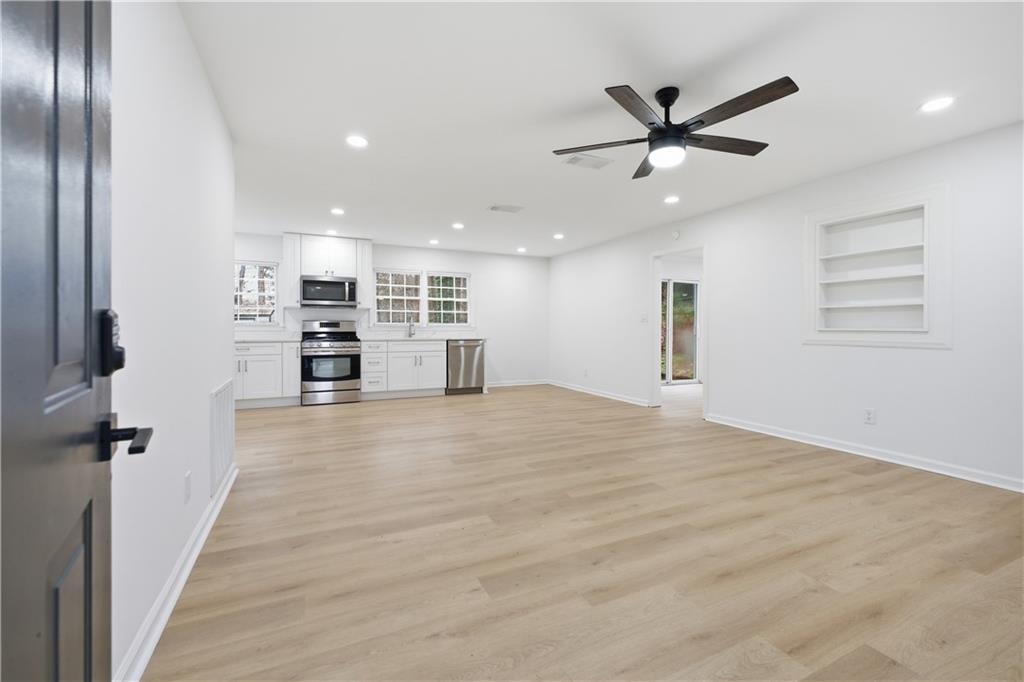 2095 Mulkey Road Southwest Marietta, GA 30008 - Photo 5 of 32 an empty room with wooden floor a ceiling fan and windows