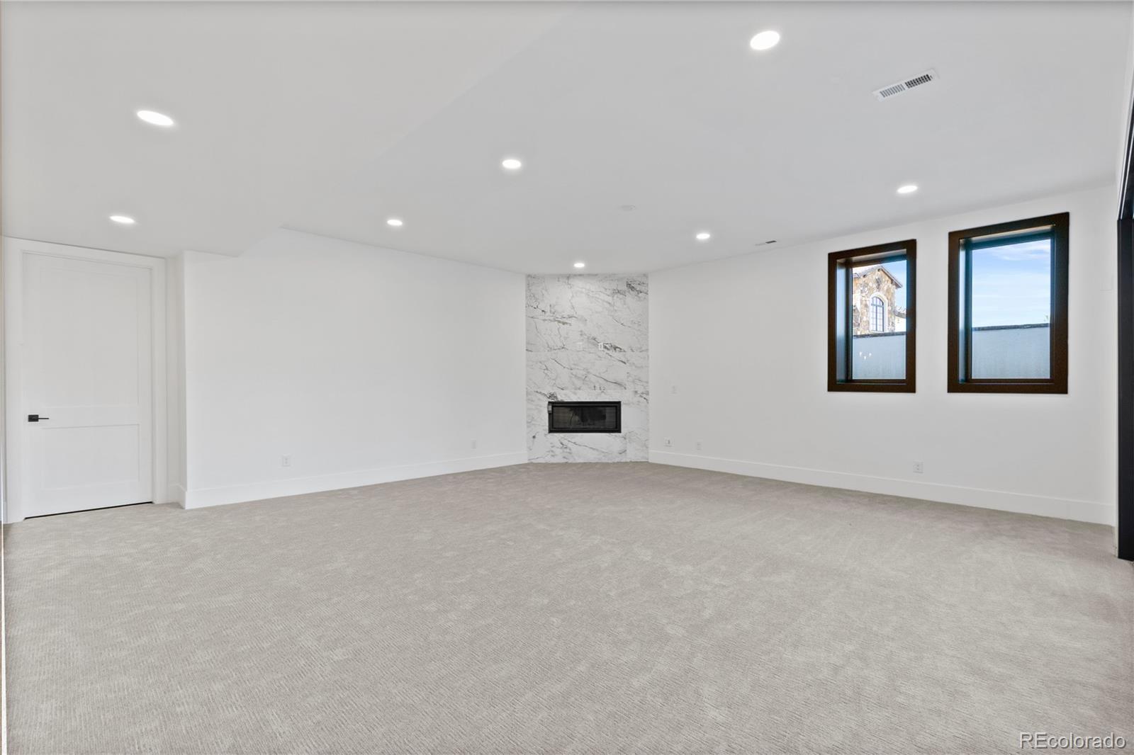 8103 Raphael Lane Littleton, CO 80125 - Photo 28 of 31 an empty room with a fireplace and windows