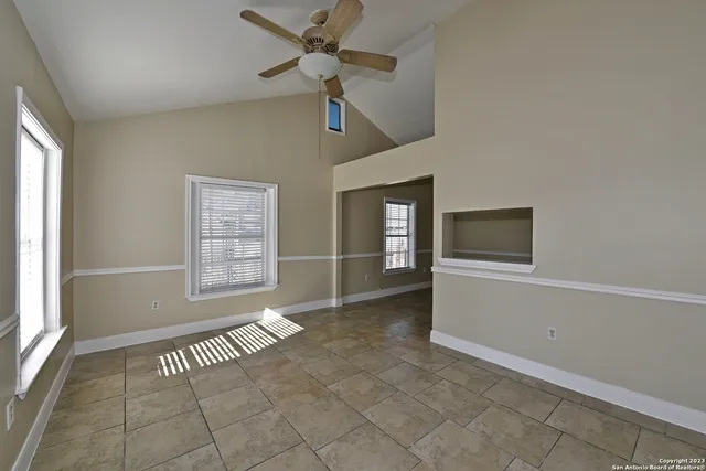 an empty room with windows and ceiling fan