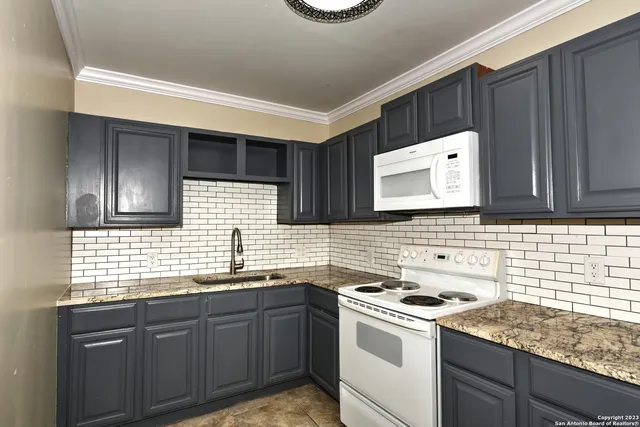a kitchen with granite countertop a sink a stove and cabinets