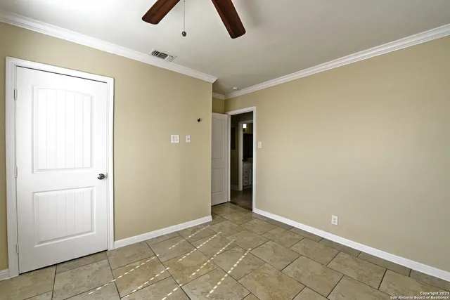 an empty room with ceiling fan and window