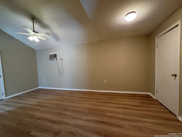 an empty room with wooden floor chandelier fan and windows