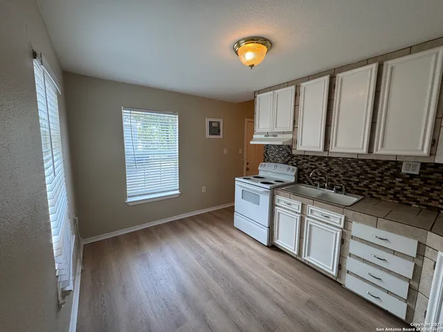 a kitchen with granite countertop white cabinets and wooden floor