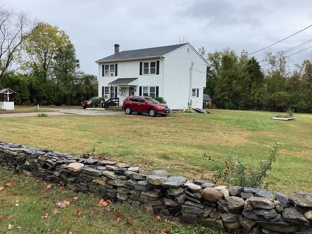 a view of a big house with a big yard and large trees