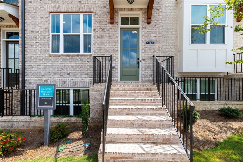 3237 Bartee Walk, Unit 202 Suwanee, GA 30024 - Photo 1 of 1 a view of a brick house with large windows and a flower garden