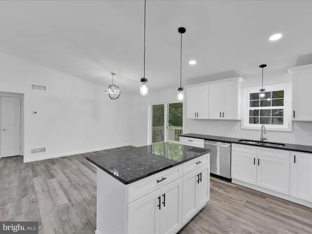 a kitchen with granite countertop a sink a counter space appliances and cabinets