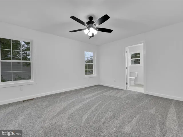 an empty room with windows and ceiling fan