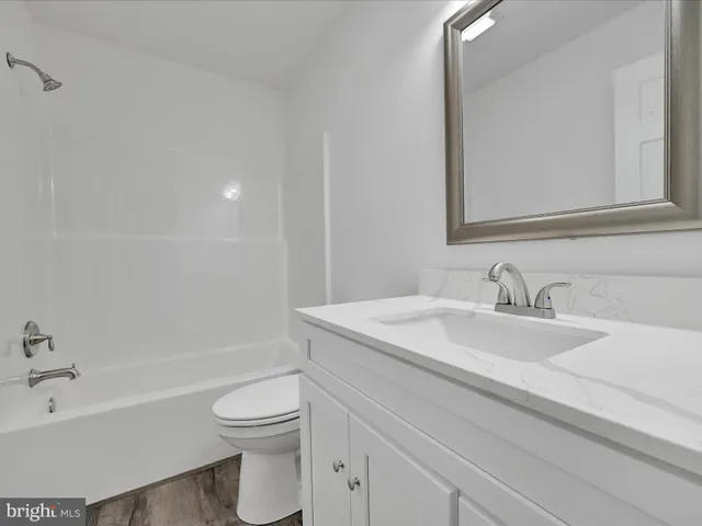 a bathroom with a granite countertop sink a toilet and a bathtub