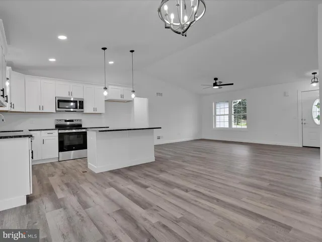 a kitchen with stainless steel appliances granite countertop a stove a sink dishwasher and a refrigerator with wooden floor