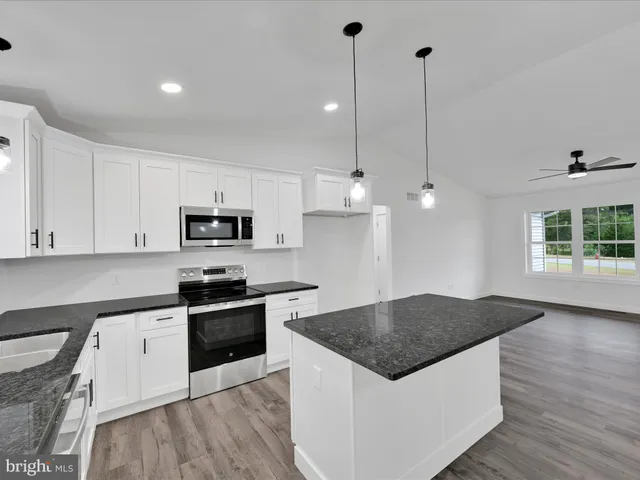 a kitchen with stainless steel appliances granite countertop a sink a stove a refrigerator and island with wooden floor