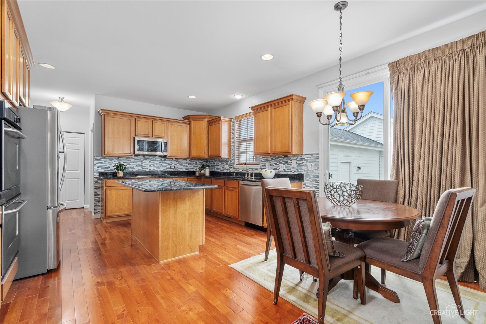 147 Gillett Street Sugar Grove, IL 60554 - Photo 16 of 32 a kitchen with granite countertop a table chairs stove microwave and cabinets