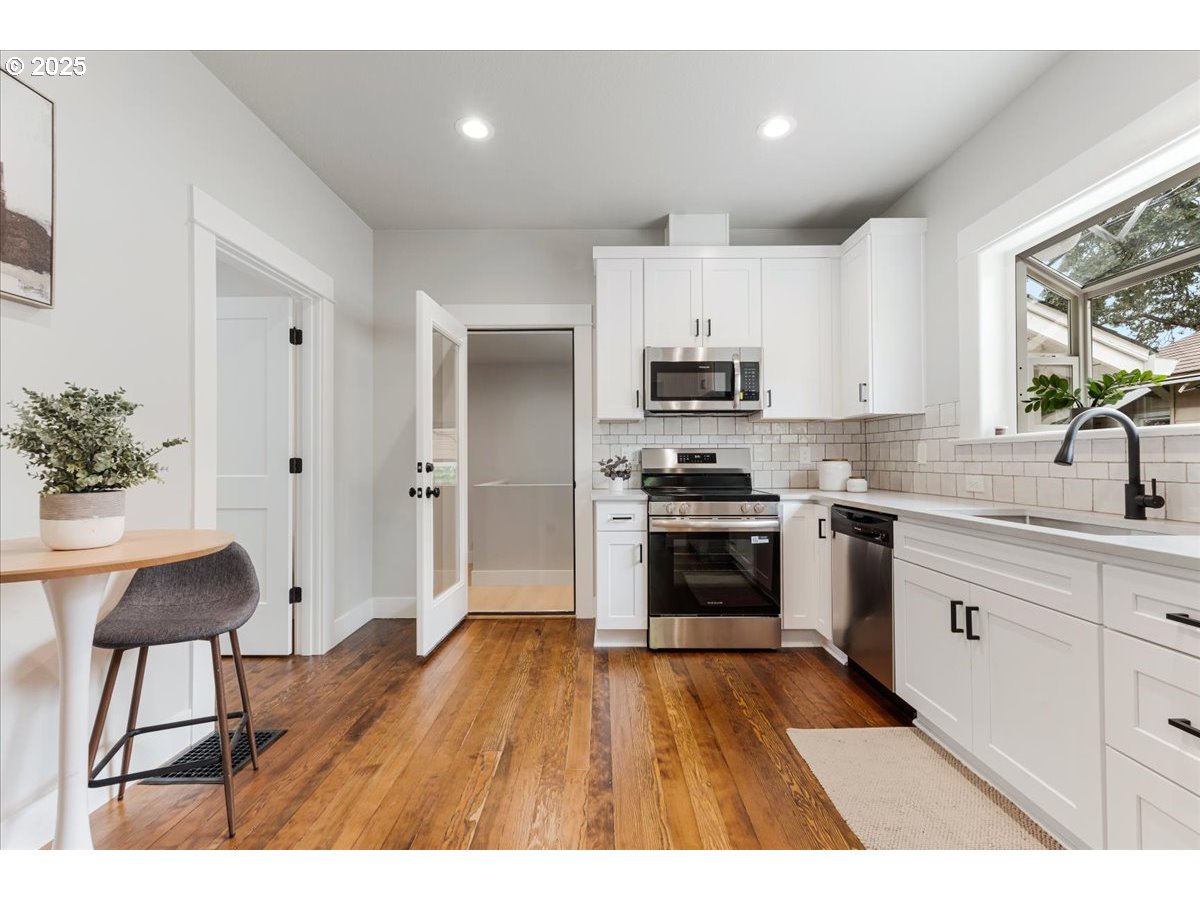 7216 North Ivanhoe Street Portland, OR 97203 - Photo 10 of 30 a kitchen with stainless steel appliances a stove a sink cabinets and a wooden floor