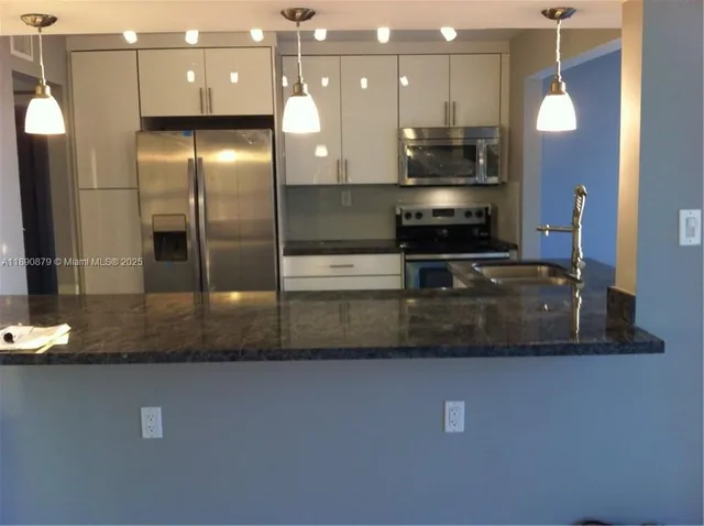 a large kitchen with stainless steel appliances a large counter top