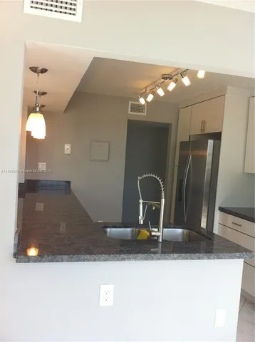 a bathroom with a sink a light fixture and a granite counter top