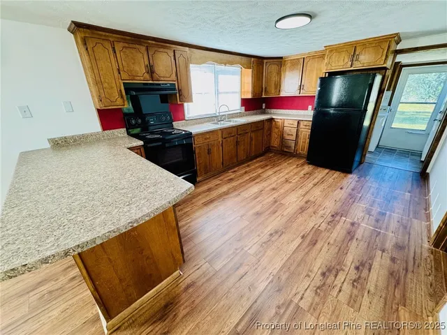 a kitchen with stainless steel appliances granite countertop a refrigerator a sink dishwasher a stove and white countertops with wooden floor