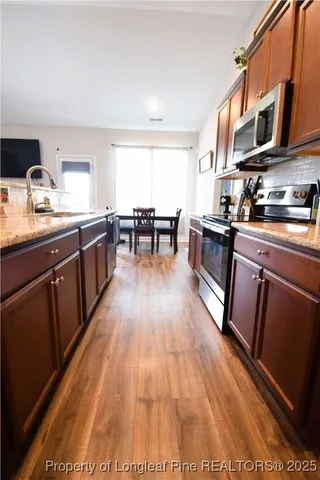 a kitchen with stainless steel appliances granite countertop a stove top oven a sink dishwasher and cabinets with wooden floor