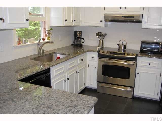 7521 Wilderness Road Raleigh, NC 27613 - Photo 2 of 11 a kitchen with stainless steel appliances granite countertop a stove a sink and white cabinets