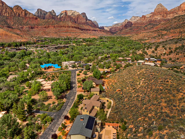 105 River Bend Circle, Unit 105 Springdale, UT 84767 - Photo 52 of 56 Expansive aerial capturing a neighborhood with varied architectural styles set against a backdrop of towering red rock formations and a lush green valley