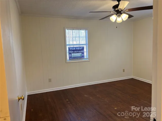 an empty room with wooden floor closet fan and windows