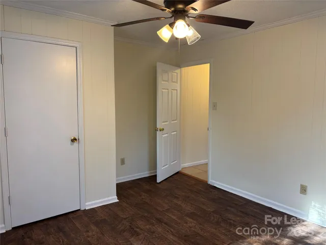 an empty room with wooden floor closet and fan