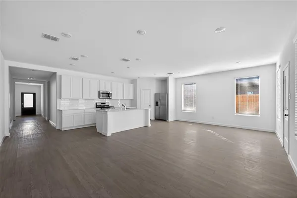 a view of a kitchen with a sink and dishwasher a stove top oven with wooden floor