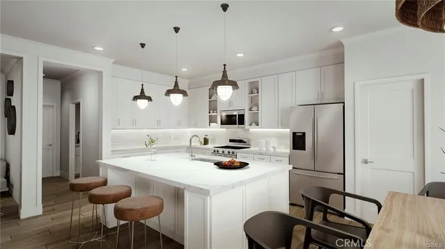 a kitchen with stainless steel appliances kitchen island granite countertop a dining table chairs and a refrigerator