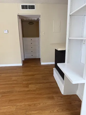 a view of kitchen and empty room with wooden floor