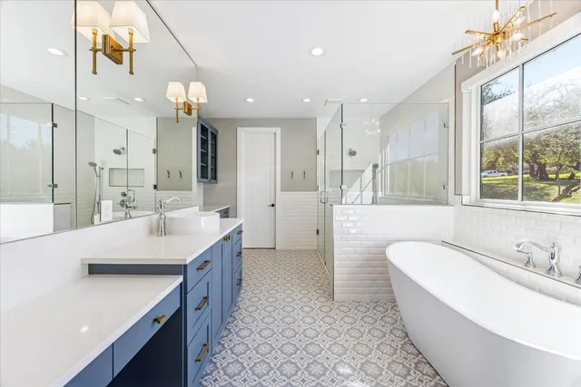 a bathroom with a tub a sink and a large mirror