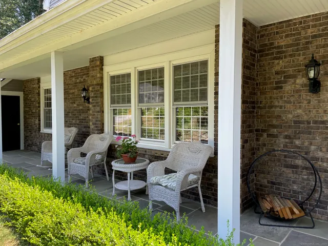 a balcony with couple of chairs and a potted plant
