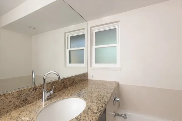 a bathroom with a granite countertop sink and mirror
