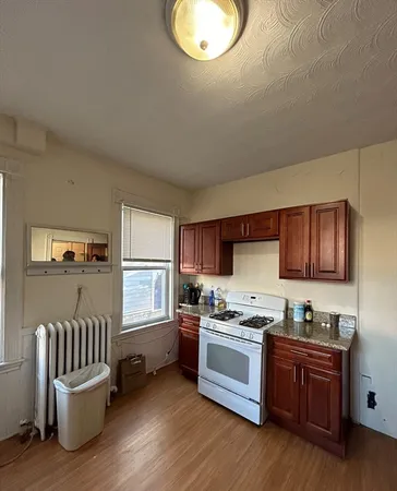a kitchen with granite countertop a refrigerator cabinets and wooden floor